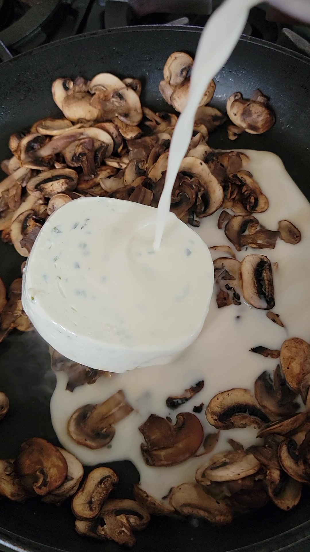 Adding almond milk to the vegan chive cream cheese and sautéed mushrooms.