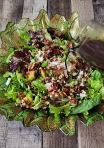 Pouring the rich honey balsamic dressing over Lindsey's Grilled Peach Salad.